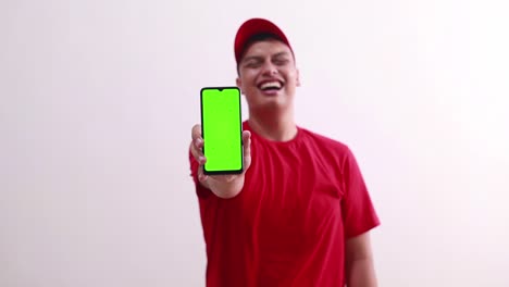 Funny-young-asian-courier-holding-a-phone-and-showing-green-screen-display