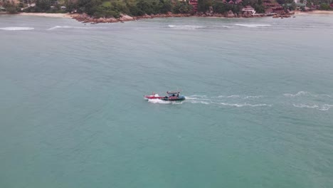 Aerial-View-Of-Fishing-Boat-Sailing-With-Pull-Back-Reveal-To-Show-Koh-Phangan-Island-In-Background