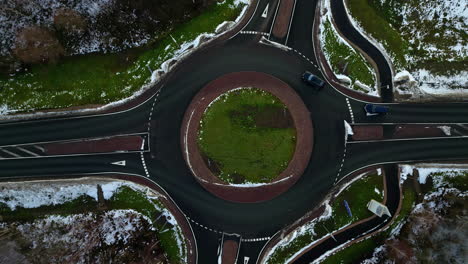 Cars-driving-on-roundabout-in-early-winter-season,-aerial-top-down-view