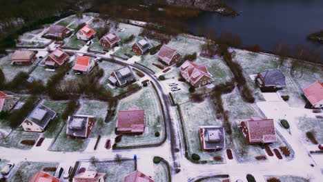 Luxury-houses-in-winter-landscape-with-snow-next-to-river-top-down-aerial