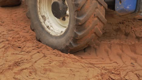 Close-up-of-big-tractor-wheel-driving-on-soft-sand-ground