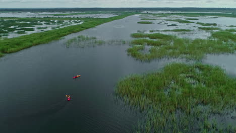 People-kayaking-in-endless-moorland,-aerial-drone-view