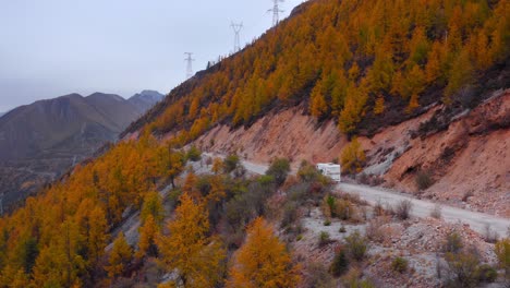 Motorhome-driving-on-a-mountainside-road-with-autumn-colored-trees