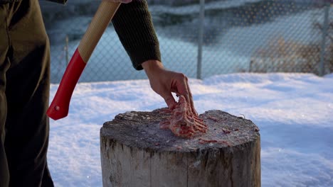 Man-uses-axe-to-chop-deer-backbone-into-pieces-for-bone-broth,-slow-motion
