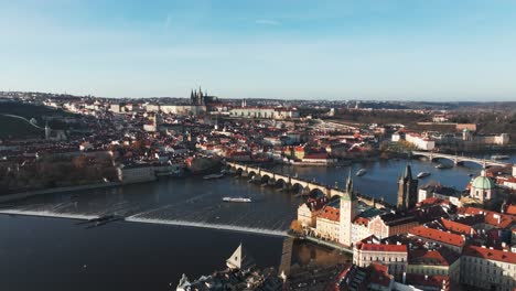 Aerial-view-over-river,-Old-town-red-rooftops-and-Prague-city-skyline