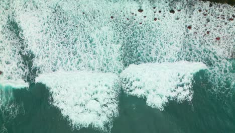 Aerial-top-down-shot-of-foamy-waves-reaching-shoreline-of-Madeira