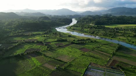 Orbiting-aerial-view-of-picturesque-provincial-farmlands-and-rice-paddies-with-winding-river-and-lush-mountains