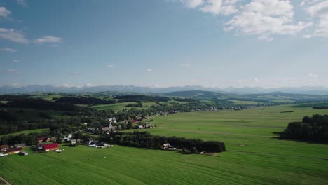 Aerial-Shot-of-Polish-Tatra-Mountains-and-Green-Fields-in-Countryside-on-a-Sunny-Day-4k
