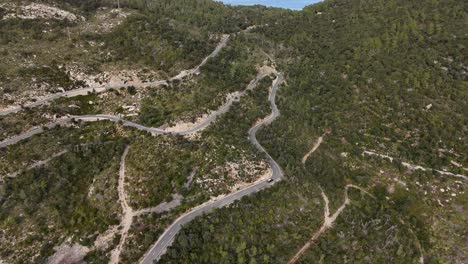 Drone-shot-of-driving-cars-on-the-winding-road-in-the-Esporles-valley-on-the-island-village-of-Mallorca-in-the-Serra-de-Tramuntana,-Spain