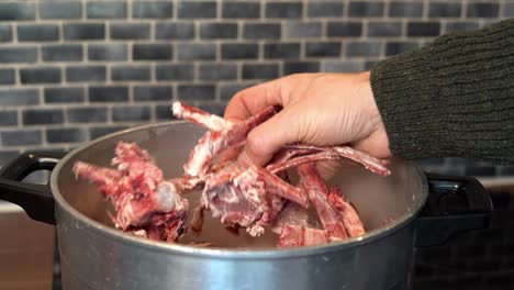 Person-picking-up-bones-for-bone-broth-out-of-soup-pot,-showing-to-camera