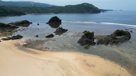 Aerial-dolly-shot-of-low-tide-coastline-of-white-sand-beach-resort-with-large-rocks-and-reefs-in-Baras,-Catanduanes