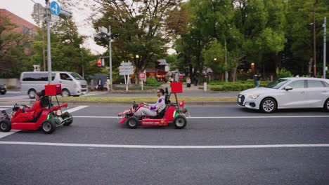 Tokyo-Minato-ward-street-Go-karts-driving-past-and-waving-to-pedestrians-in-early-evening