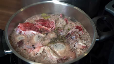 Bone-broth,-seasoned-with-herbs-and-spices,-simmering-in-pot-on-stove-top