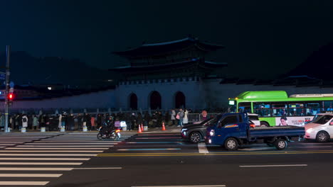 Traffic-Time-Lapse-at-Gwanghwamun-Square-During-Seoul-Light-Gwanghwamun-Festival,-Croud-of-People-Watch-Lights-Projection-on-Gwanghwamun-Gate-at-Night-in-Winter---zoom-out