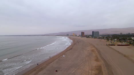 Drone-shot-flying-along-the-beach-in-Arica,-Chile-on-a-cloudy-day