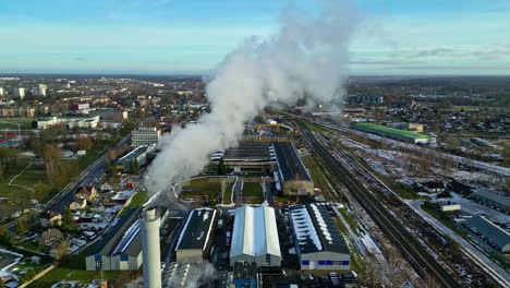 Factory-emits-smoke-over-small-township,-aerial-drone-view