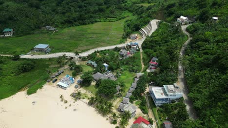 Stunning-aerial-dolly-of-hillside-roads-in-Puraran-beach-resort,-Baras-with-tropical-greenery-and-small-huts