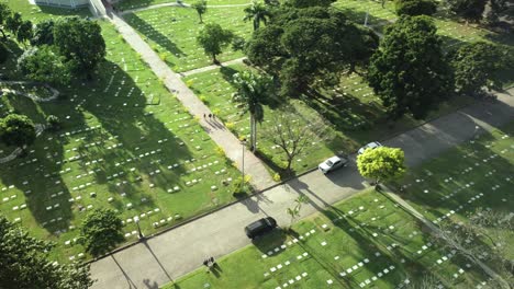 Drone-shot-of-people-walking-in-the-cemetery-towards-the-road