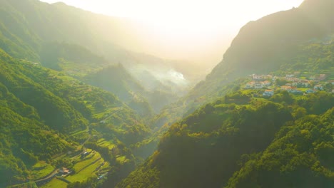 Cinematic-drone-flight-between-beautiful-idyllic-mountain-landscape-of-Madeira-and-village-on-slope-at-sunset-sunlight
