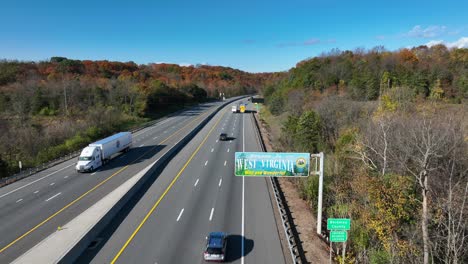 Welcome-to-West-Virginia-state-sign-along-interstate-highway-surrounded-by-colorful-fall-foliage-in-Appalachia