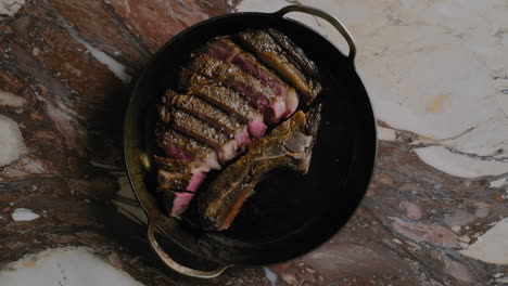 Draufsicht-Auf-Ein-Ribeye-Steak,-Das-In-Einer-Gusseisernen-Pfanne-Angerichtet-Wird