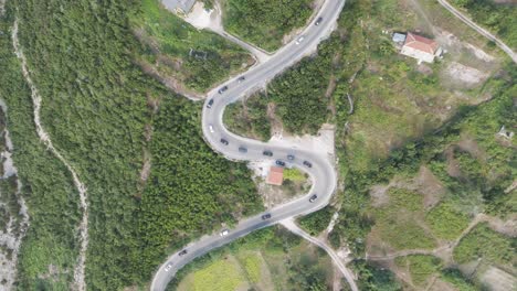 High-aerial-top-down-view-of-cars-drive-on-Albanian-serpentine-road-in-line