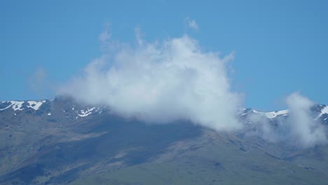 Serene-cloud-drift-near-majestic-mountain-range,-creating-a-breathtaking-alpine-vista