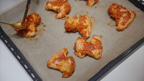 Coating-chicken-wings-with-hot-sauce-placed-on-a-baking-sheet