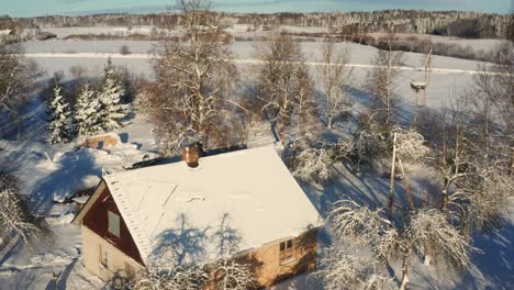 Aerial-view-of-snowy-countryside-cottage-roof-and-smoke-come-out-from-chimney