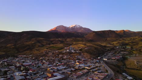 Drone-shot-flying-over-the-small-town-of-Putre-in-Chile-at-an-altitude-of-3650-meters-with-the-Taapacá-volcano-in-the-background-at-sunset