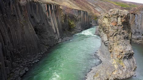 Aerial-view-of-fast-streaming-water-in-a-steep-canyon-in-Iceland-on-a-sunny-day