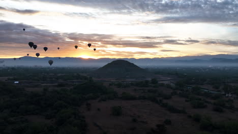 Pyramid-and-Hot-air-Balloons,-sunrise-in-Teotihuacan,-Mexico---orbit,-drone-shot