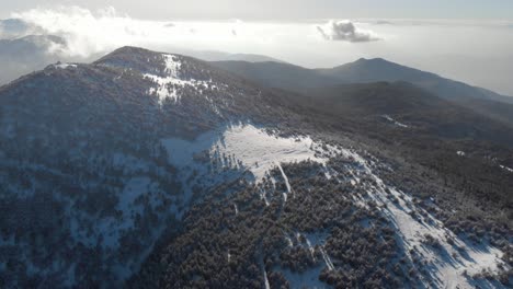 Drone-Descendiendo-Sobre-La-Capa-De-Nieve-Cresta-De-La-Montaña-Día-Soleado-De-Invierno