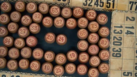 Cinematic-close-up-smooth-shot-from-above-of-a-pile-of-Bingo-wooden-barrels-in-a-square,-woody-figures,-old-numbers-background,-vintage-board-game,-slow-motion-120-FPS-commercial-video-pan-right