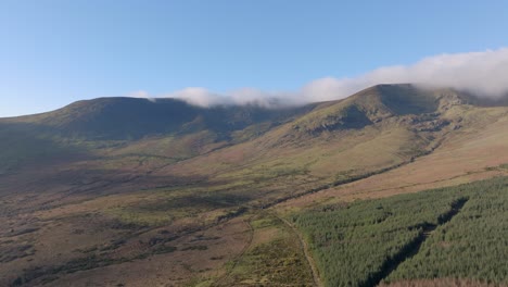 Paisaje-De-Drones-Ladera-De-La-Montaña-Con-Nubes-Bajas-Cielos-Azules-En-Invierno-Montañas-Comeragh-Waterford-Irlanda
