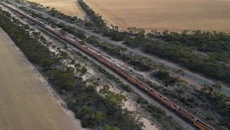 Aerial-Tracking-shot-of-long-iron-industrial-cargo-train-on-railroad-in-Australian-countryside