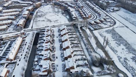 Beautiful-aerial-of-a-snowy-suburban-neighborhood-with-a-snow-covered-park-and-icy-ponds