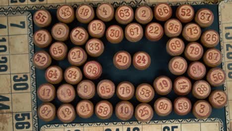 Cinematic-close-up-smooth-shot-from-above-of-a-pile-of-Bingo-wooden-barrels-in-a-square,-woody-figures,-old-numbers-background,-vintage-board-game,-slow-motion-120-FPS-commercial-gimbal-tilt-up