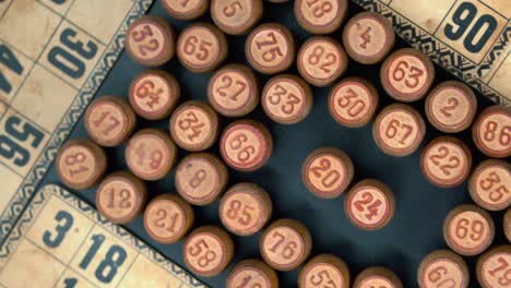 Cinematic-rotating-smooth-shot-from-above-of-a-pile-of-Bingo-wooden-barrels-in-a-square,-woody-figures,-old-numbers-background,-vintage-board-game,-professional-lighting,-4K-video
