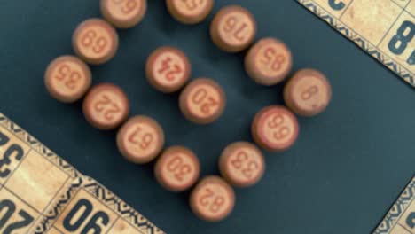 Cinematic-rotating-smooth-zoom-out-shot-from-above-of-a-Bingo-wooden-barrels-in-a-square,-woody-figures,-old-numbers-background,-vintage-board-game,-professional-lighting,-slow-motion-4K-video