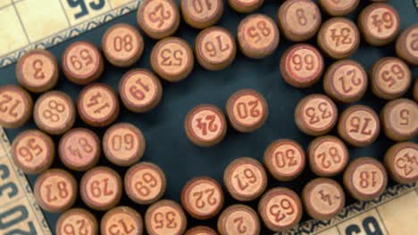 Cinematic-close-up-rotating-smooth-zoom-out-shot-from-above-of-a-pile-of-Bingo-wooden-barrels-in-a-square,-woody-figures,-old-numbers-background,-vintage-board-game,-professional-lighting,-4K-video