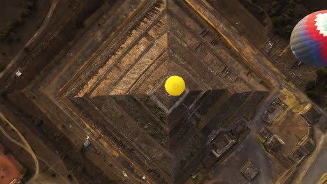 Top-down-drone-shot-of-Hot-air-balloons-above-a-Pyramid-in-sunny-Teotihuacan,-Mexico