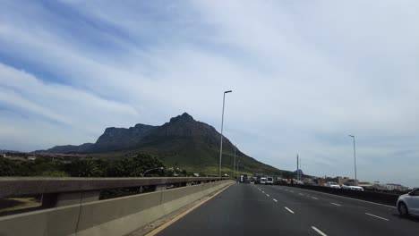 Conduciendo-Por-El-Puente-De-Carretera-En-Ciudad-Del-Cabo-Con-La-Montaña-De-La-Mesa-Al-Fondo,-Sudáfrica