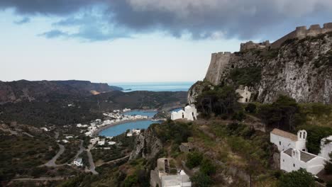 Flyby-next-to-Chora-Castle-Walls-Revealing-Kapsali-Bay,-Kythira-Island,-Greece