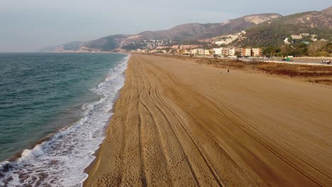 Castelldefels-Beach-near-Barcelona,-with-golden-sands-and-gentle-waves,-quiet,-scenic,-aerial-view