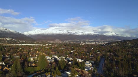 Drone-shot-flying-over-the-wealthy-suburbs-of-Santiago-de-Chile-with-the-snow-covered-Andes-mountains-in-the-background