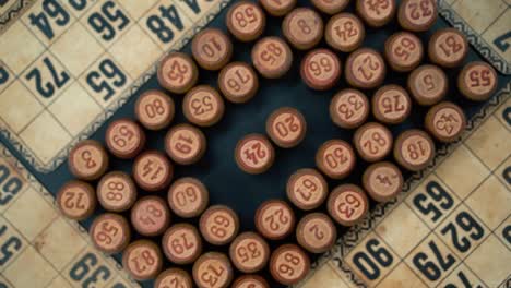 Cinematic-close-up-smooth-shot-from-above-of-a-pile-of-Bingo-wooden-barrels-in-a-square,-woody-figures,-old-numbers-background,-vintage-board-game,-slow-motion-120-FPS-commercial-rotating-zoom-in