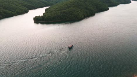 Scenic-aerial-view-of-tourist-boat-cruise-on-Albanian-river-near-mountain-forest