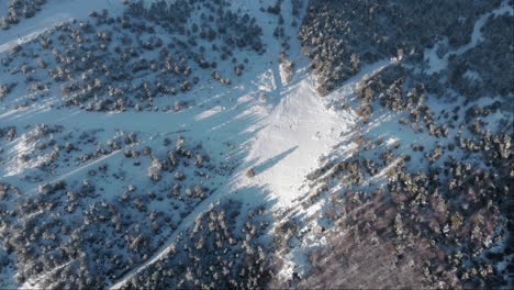 Top-Down-aerial-view-snow-covered-ski-slope-empty-of-people-sunset