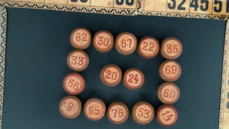 Cinematic-close-up-rotating-zoom-out-shot-from-above-of-a-Bingo-wooden-barrels-in-a-square,-woody-figures,-old-numbers-background,-vintage-board-game,-professional-lighting,-4K-video